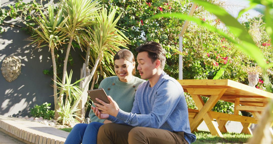 Young Couple Using Tablet in Lush Outdoor Garden - Free Images, Stock Photos and Pictures on Pikwizard.com