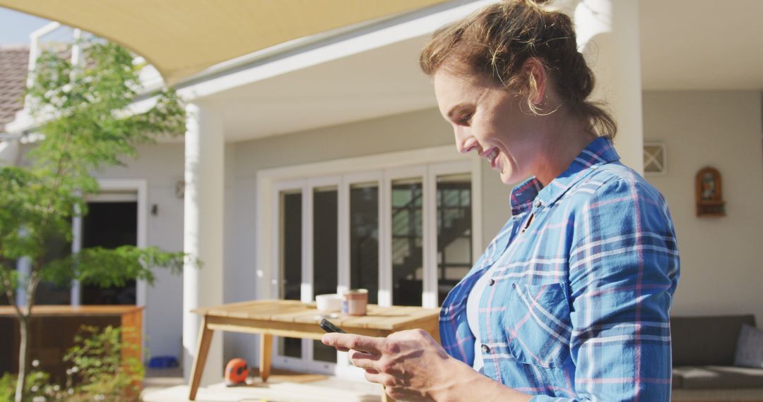 Woman Smiling and Using Smartphone in Backyard - Free Images, Stock Photos and Pictures on Pikwizard.com