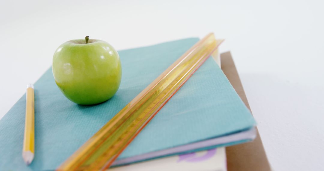 Green Apple on Books with Pencil and Ruler Symbolizing Education
