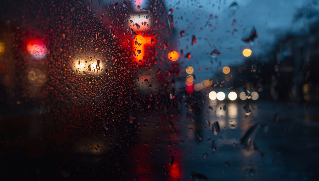 Rain-Streaked Window with Neon and Headlights Reflections at Dusk