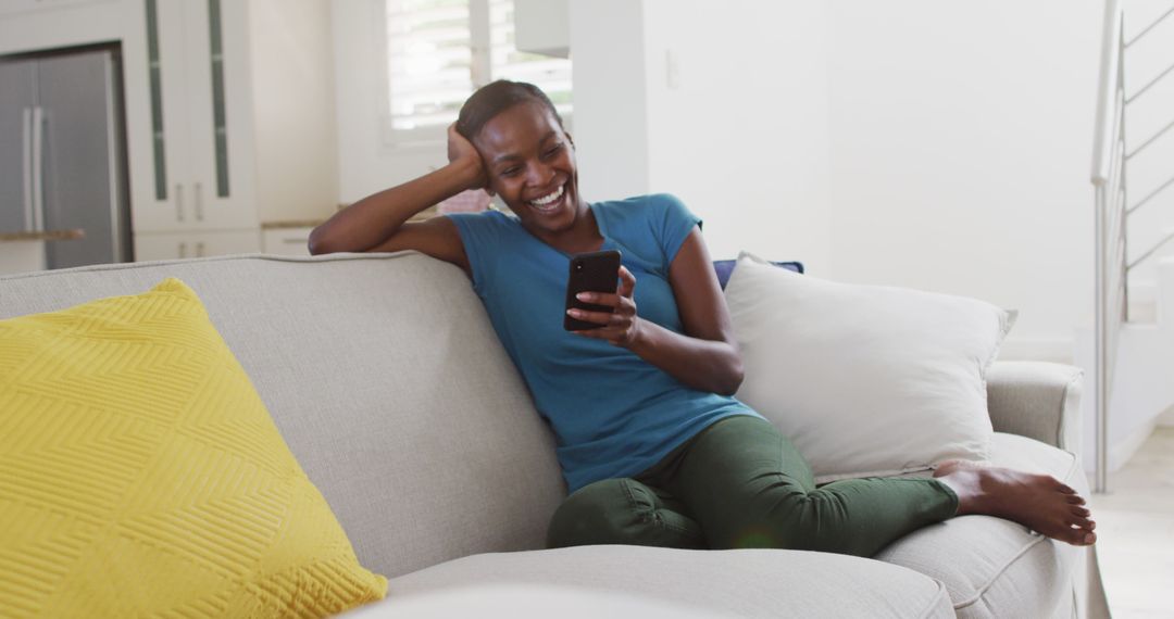 Smiling Woman Relaxing On Couch At Home Texting On Smartphone - Free Images, Stock Photos and Pictures on Pikwizard.com