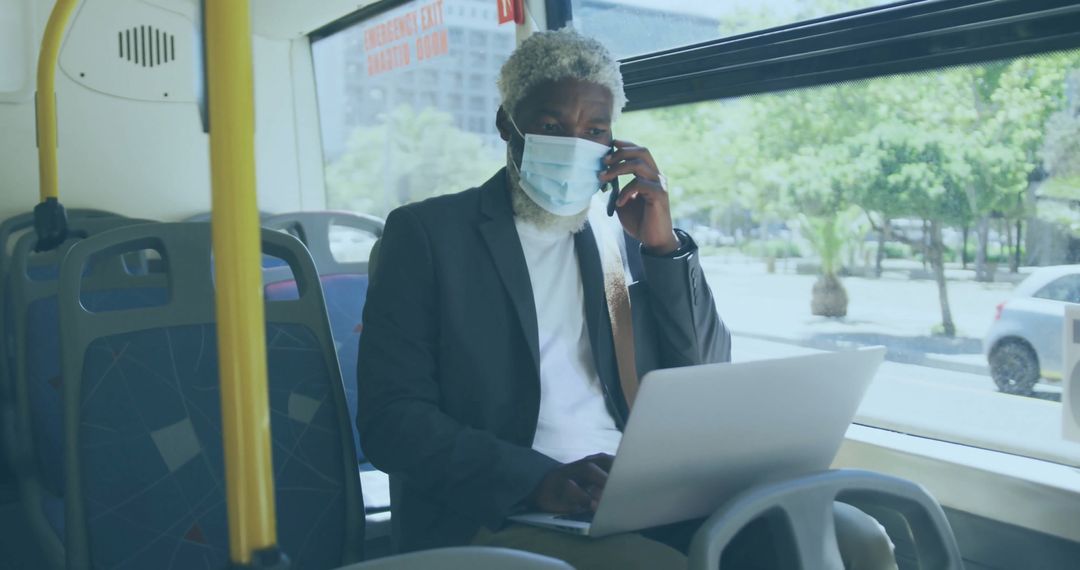 Businessman on Commute Using Laptop and Phone While Wearing Face Mask