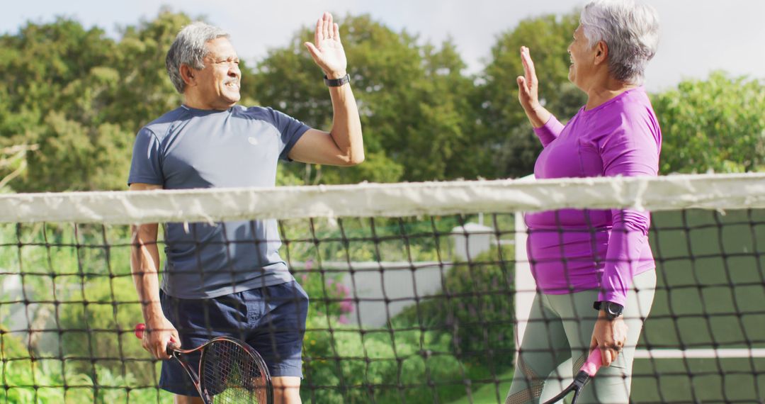 Senior couple celebrating on tennis court with high-five - Free Images, Stock Photos and Pictures on Pikwizard.com