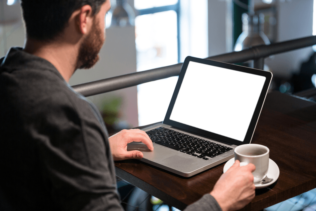 Transparent Display of Man Using Laptop and Holding Coffee Cup in Restaurant