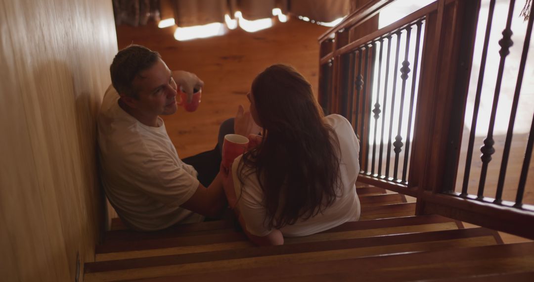 Couple Relaxing on Stairs Sharing Coffee at Home