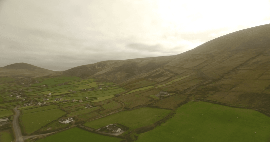 Tranquil Hillside Landscape with Lush Green Fields and Overcast Sky