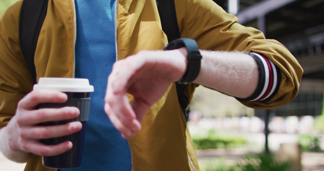 Man Holding Coffee Cup and Checking Smartwatch Outdoors - Free Images, Stock Photos and Pictures on Pikwizard.com