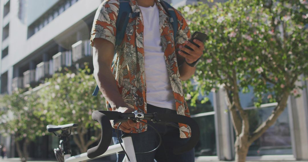 Casual Cyclist Checking Smartphone on Urban Sidewalk