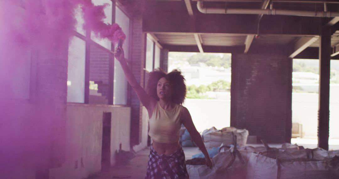 Young woman with colored smoke bomb in urban warehouse - Free Images, Stock Photos and Pictures on Pikwizard.com