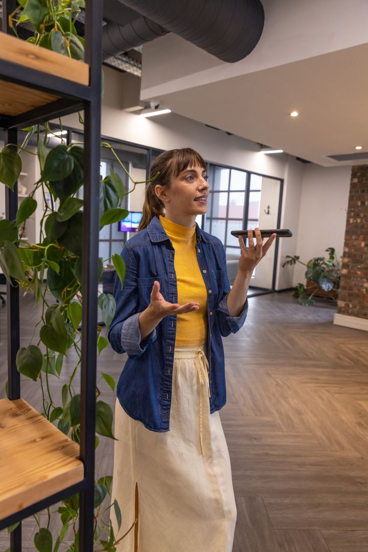 Woman Using Smartphone for Voice Commands in Modern Office Space