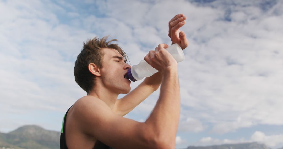 Athlete Hydrating Outdoors with Water Bottle Against Blue Sky - Free Images, Stock Photos and Pictures on Pikwizard.com