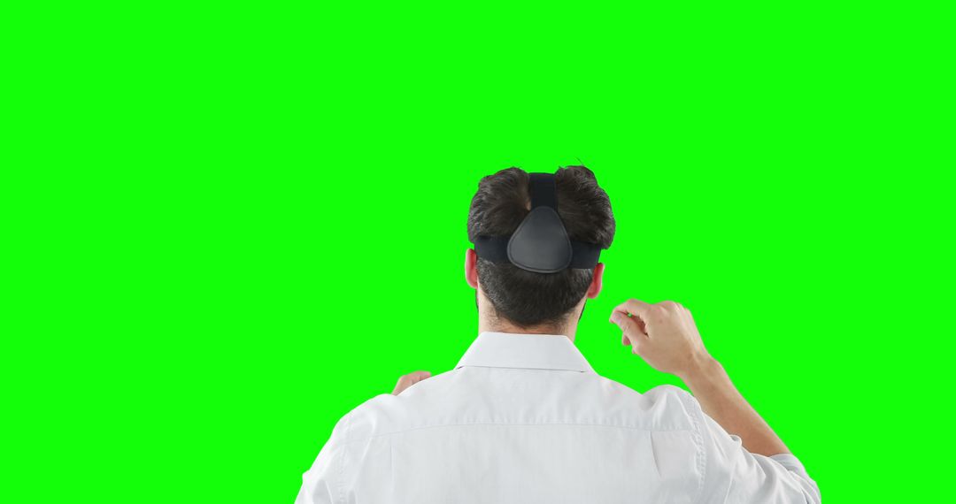 Man Immersed in Virtual Reality Against Green Backdrop