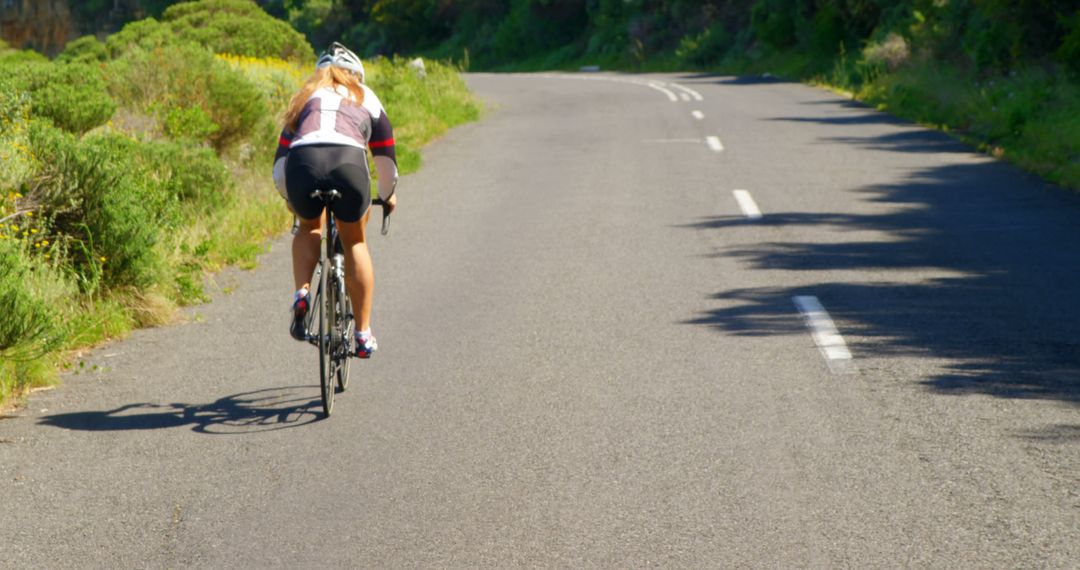 Female Cyclist Riding on Scenic Open Road Surrounded by Nature - Free Images, Stock Photos and Pictures on Pikwizard.com