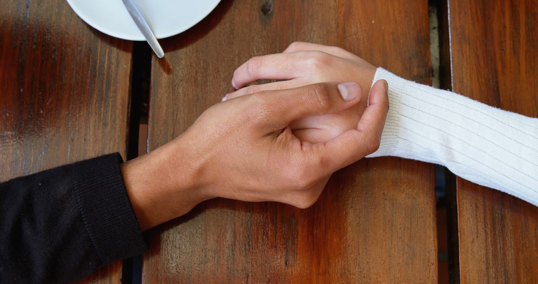 Close Up of Interracial Couple Holding Hands in Cafe