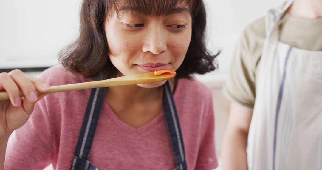 Woman Tasting Food with Wooden Spoon in Kitchen - Free Images, Stock Photos and Pictures on Pikwizard.com