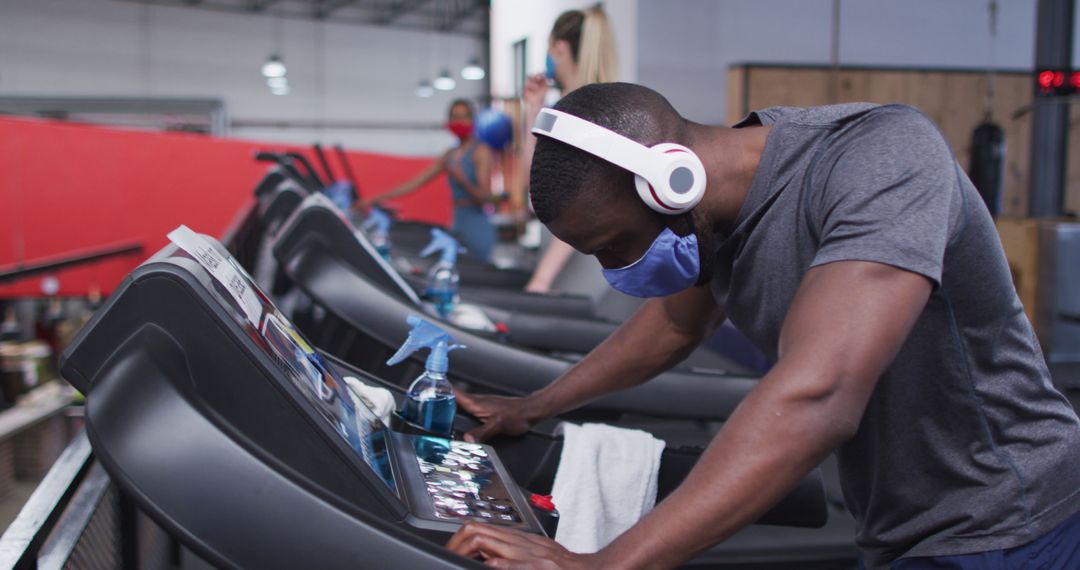 Man Exercising on Treadmill Wearing Headphones and Protective Mask at Gym - Free Images, Stock Photos and Pictures on Pikwizard.com