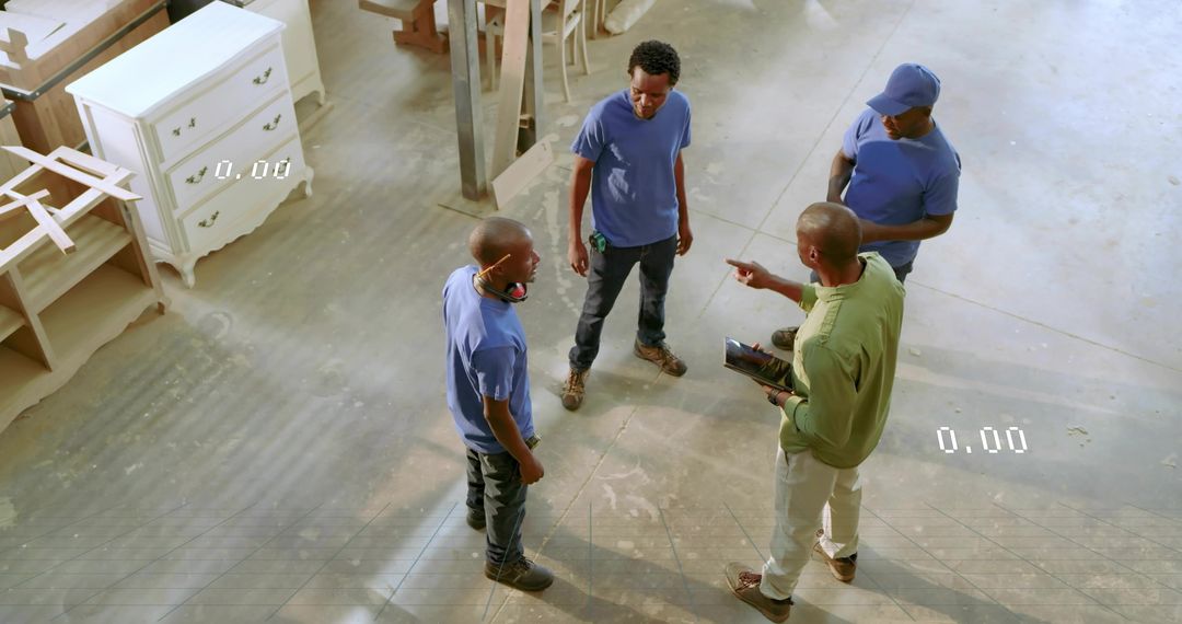 Carpentry crew discussing woodworking plans around tablet in workshop, wearing boots