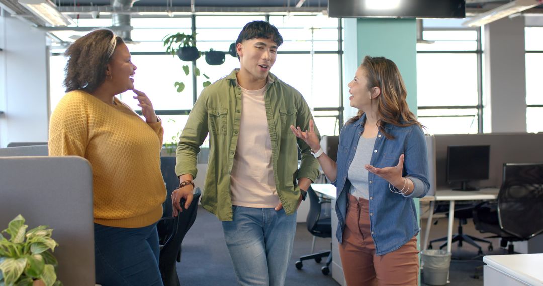 Diverse coworkers walking and talking in bright modern open office, casual teamwork