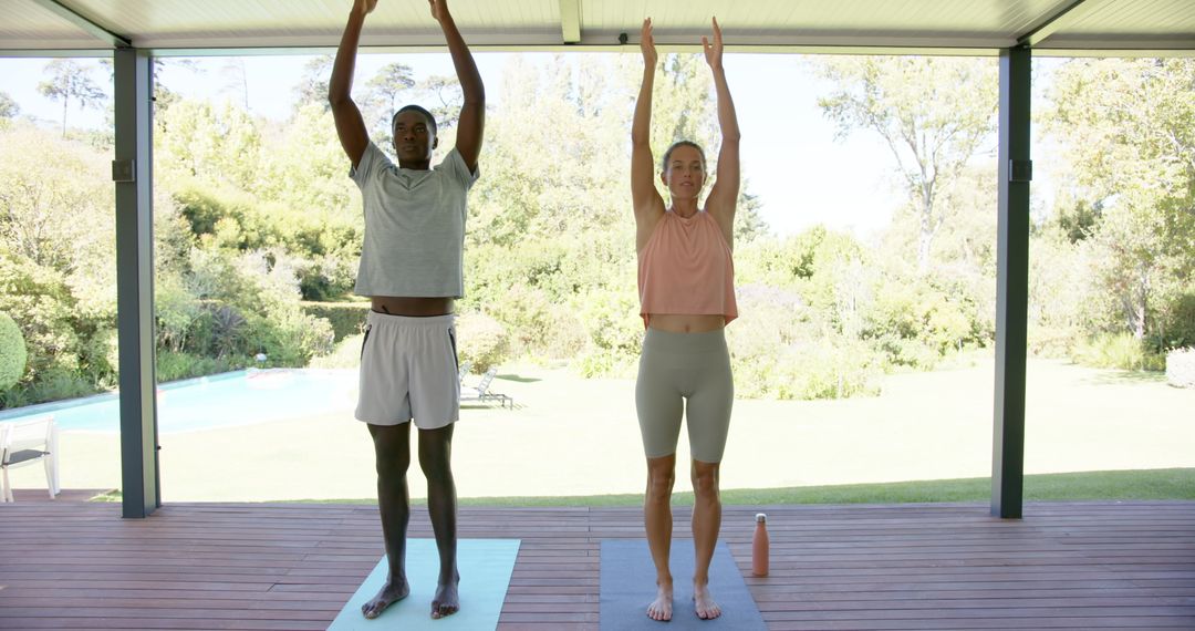 Diverse couple practicing yoga on outdoor patio in serene setting