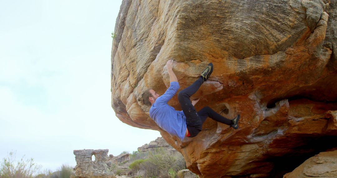 Young Man Rock Climbing Overhanging Boulders in Desert Landscape - Free Images, Stock Photos and Pictures on Pikwizard.com