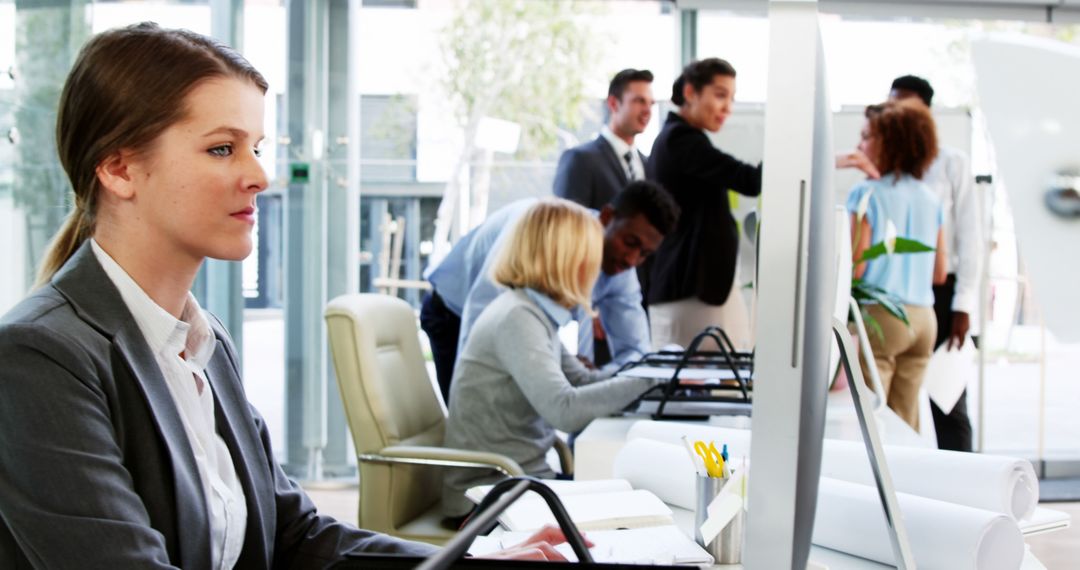 Focused Businesswoman Working at Computer in Collaborative Office