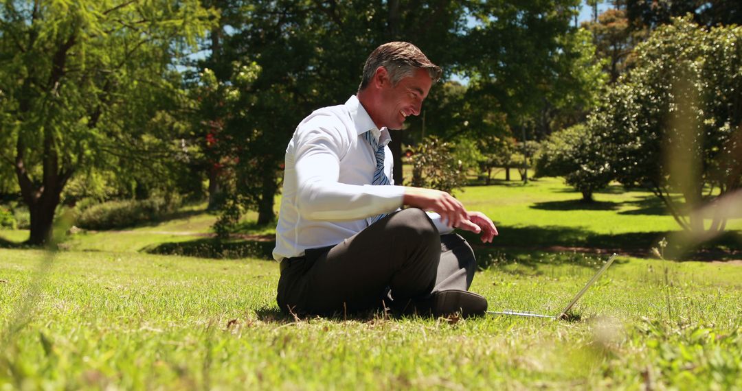 Businessman Working Outdoors on Laptop in Sunny Park - Free Images, Stock Photos and Pictures on Pikwizard.com