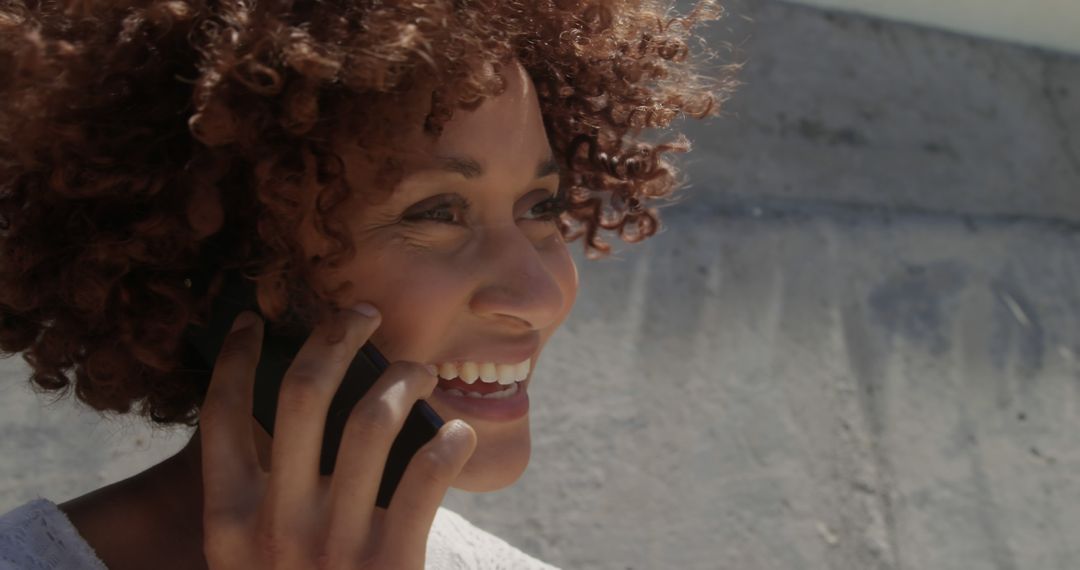 Smiling Woman with Curly Hair Talking on Phone Outside - Free Images, Stock Photos and Pictures on Pikwizard.com