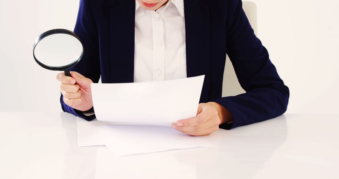 Businessperson examining documents with magnifying glass at desk - Free Images, Stock Photos and Pictures on Pikwizard.com