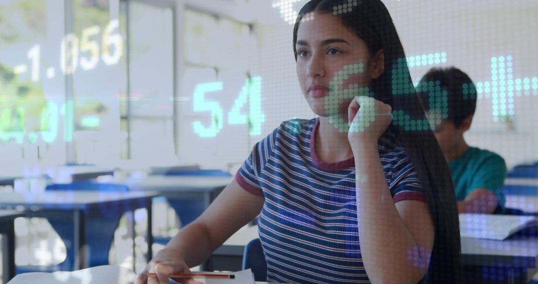 Teenage girl studying in classroom taking notes with digital data overlay and focused expression