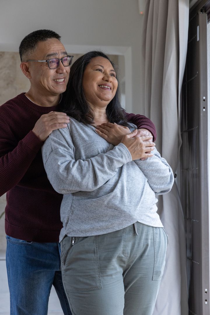 Diverse Couple Embracing by Window in Cozy Home
