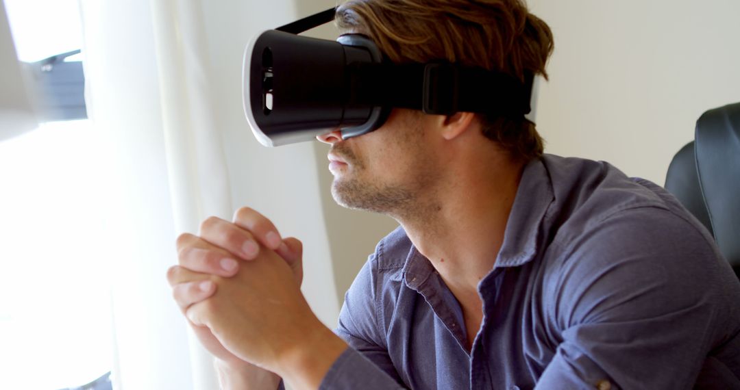 Man Using Virtual Reality Headset While Sitting at Desk - Free Images, Stock Photos and Pictures on Pikwizard.com