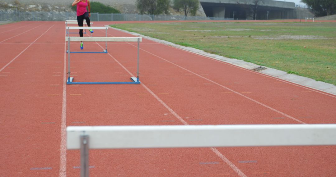 Athlete jumping over hurdles on track field - Free Images, Stock Photos and Pictures on Pikwizard.com