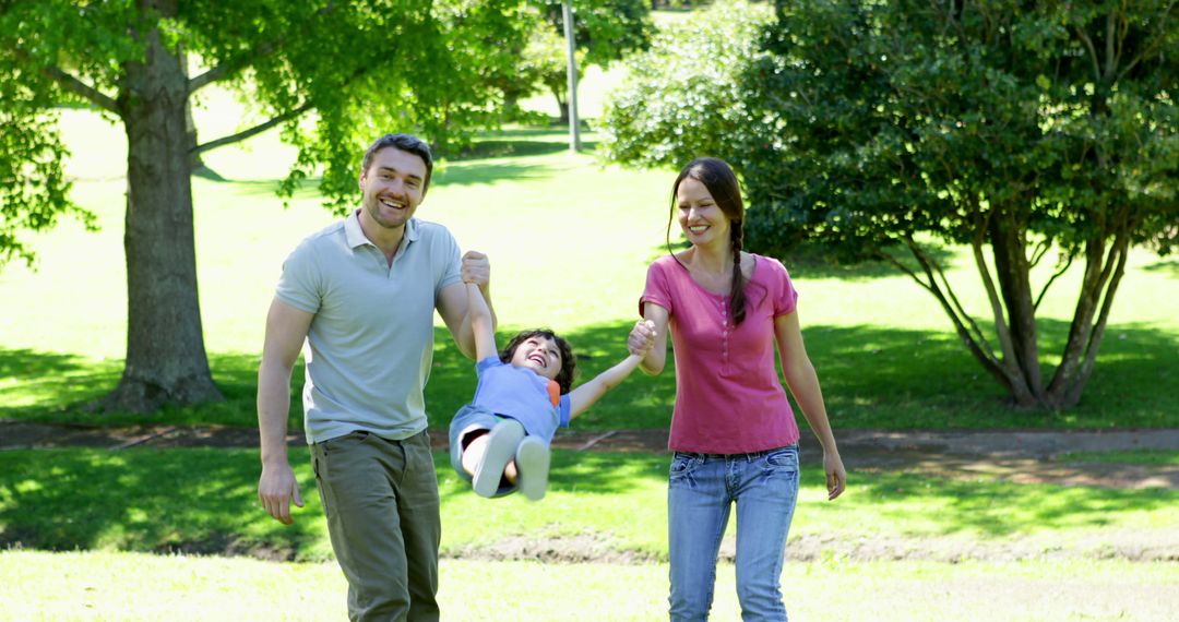 Joyful Parents Swinging Child in Outdoor Park - Free Images, Stock Photos and Pictures on Pikwizard.com