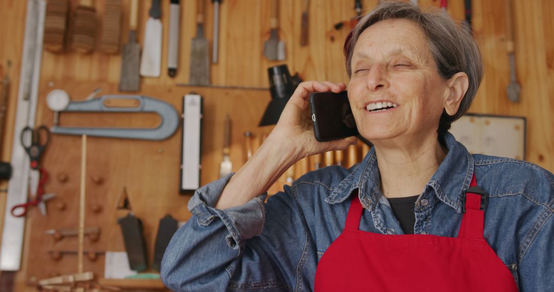 Senior Woman Carpenter Talking on Smartphone in Workshop - Free Images, Stock Photos and Pictures on Pikwizard.com