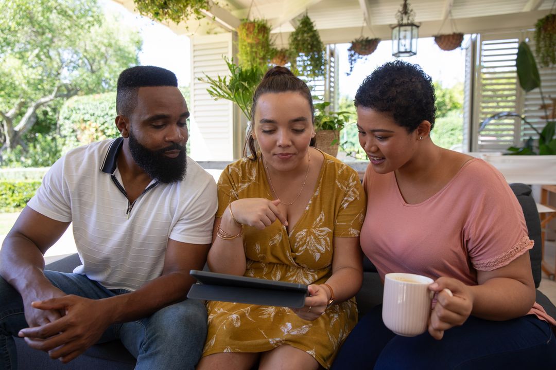 Friends Enjoying Outdoor Gathering under Pergola with Tablet