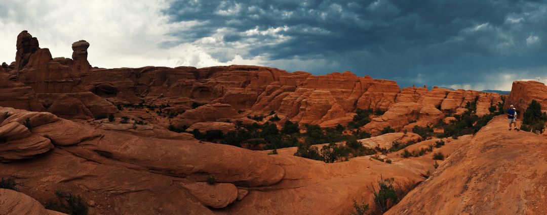 Hiking through dramatic red rock formations under stormy skies - Free Images, Stock Photos and Pictures on Pikwizard.com