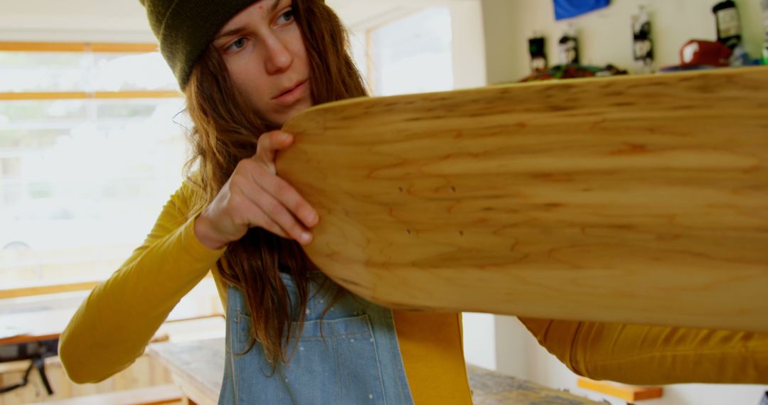 Female Carpenter Evaluating Wooden Surfboard in Workshop - Free Images, Stock Photos and Pictures on Pikwizard.com