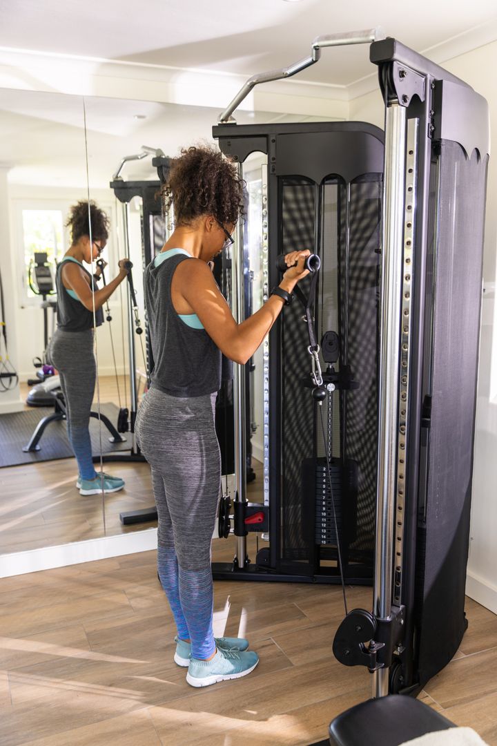 Woman Working Out on Cable Pulley in Home Gym with Mirror Reflection