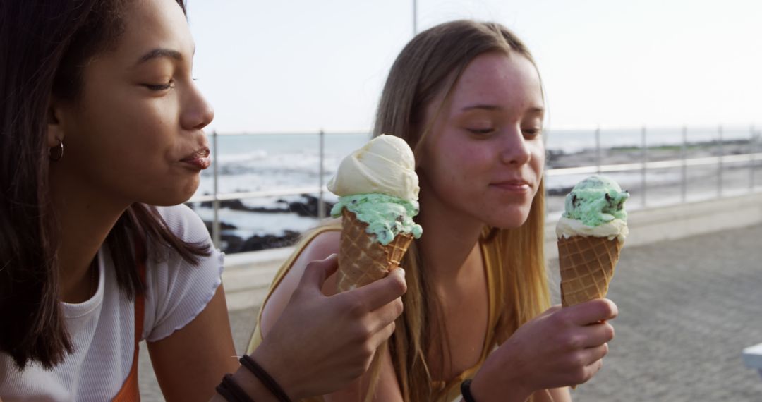 Two Teenage Friends Enjoying Ice Cream Cones by Ocean - Free Images, Stock Photos and Pictures on Pikwizard.com