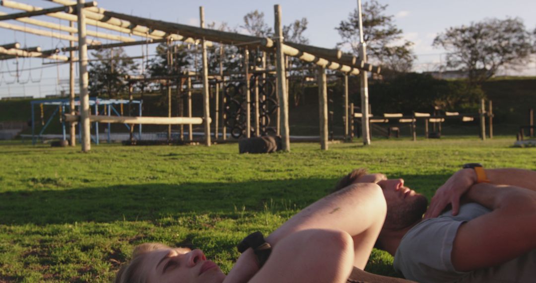 Couple Relaxing on Grass Near Obstacle Course at Park