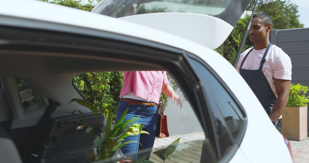 Customer and Garden Center Employee Loading Plants in Car Trunk