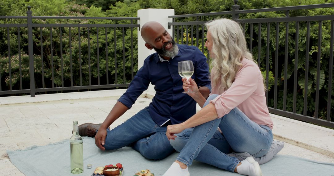 Senior Couple Enjoying Relaxing Picnic with Wine on Terrace