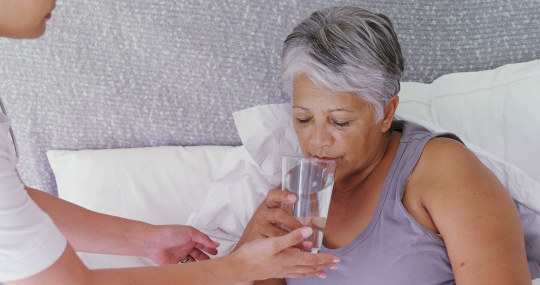 A middle-aged woman is being cared for as she drinks water from a glass, with copy space - Free Images, Stock Photos and Pictures on Pikwizard.com
