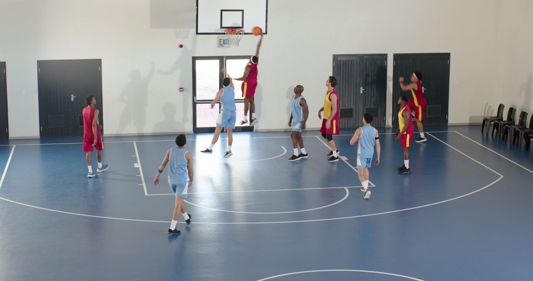 Determined Basketball Team Sees Player Dunking in Motion on Indoor Court