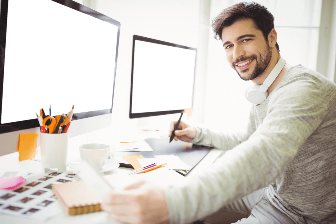 Smiling Man With Headphones Working at Desk With Transparent Screens