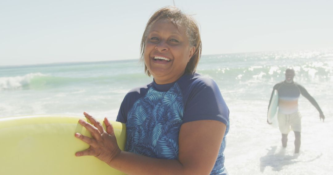 Smiling Middle-Aged Woman Holding Surfboard at Beach - Free Images, Stock Photos and Pictures on Pikwizard.com