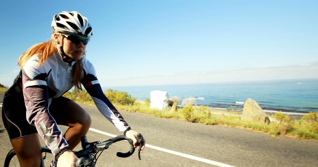 Female Cyclist Riding Along Coastal Road on Sunny Day - Free Images, Stock Photos and Pictures on Pikwizard.com