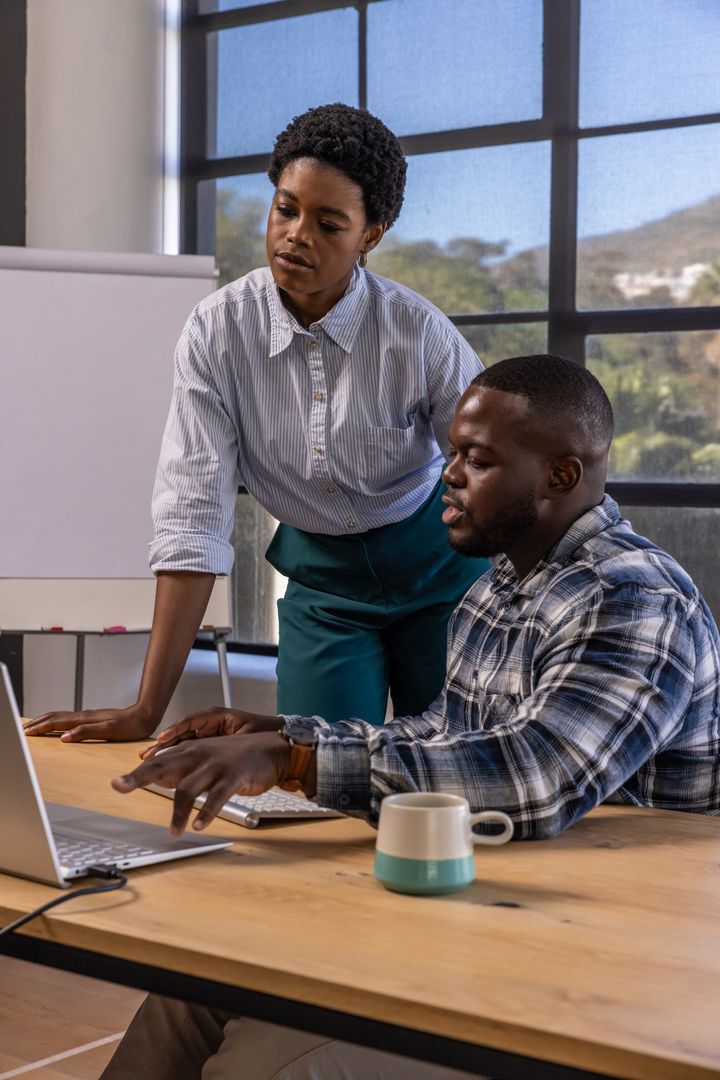 Team Collaborating Around Laptop in Modern Office Environment