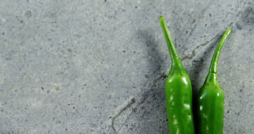 Two Green Chili Peppers on Gray Stone Background - Free Images, Stock Photos and Pictures on Pikwizard.com