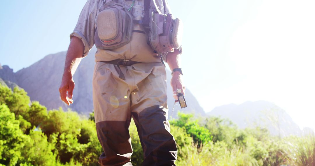 Fisherman wearing wading gear standing by mountain stream - Free Images, Stock Photos and Pictures on Pikwizard.com